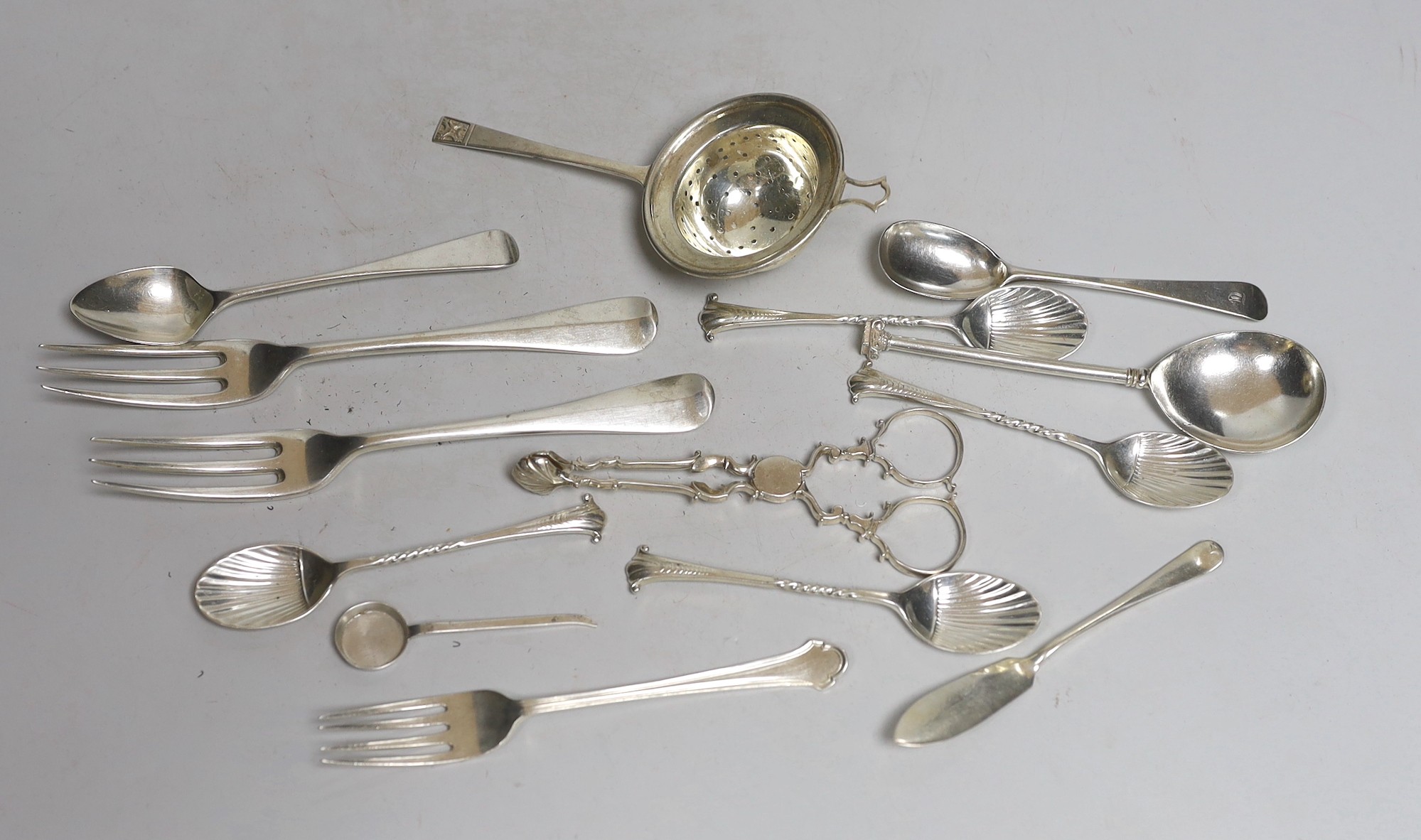 A silver tea strainer and a small collection of assorted 20th century and earlier silver cutlery, various dates and makers, including a pair of mid 18th century sugar nips, 9.7oz.